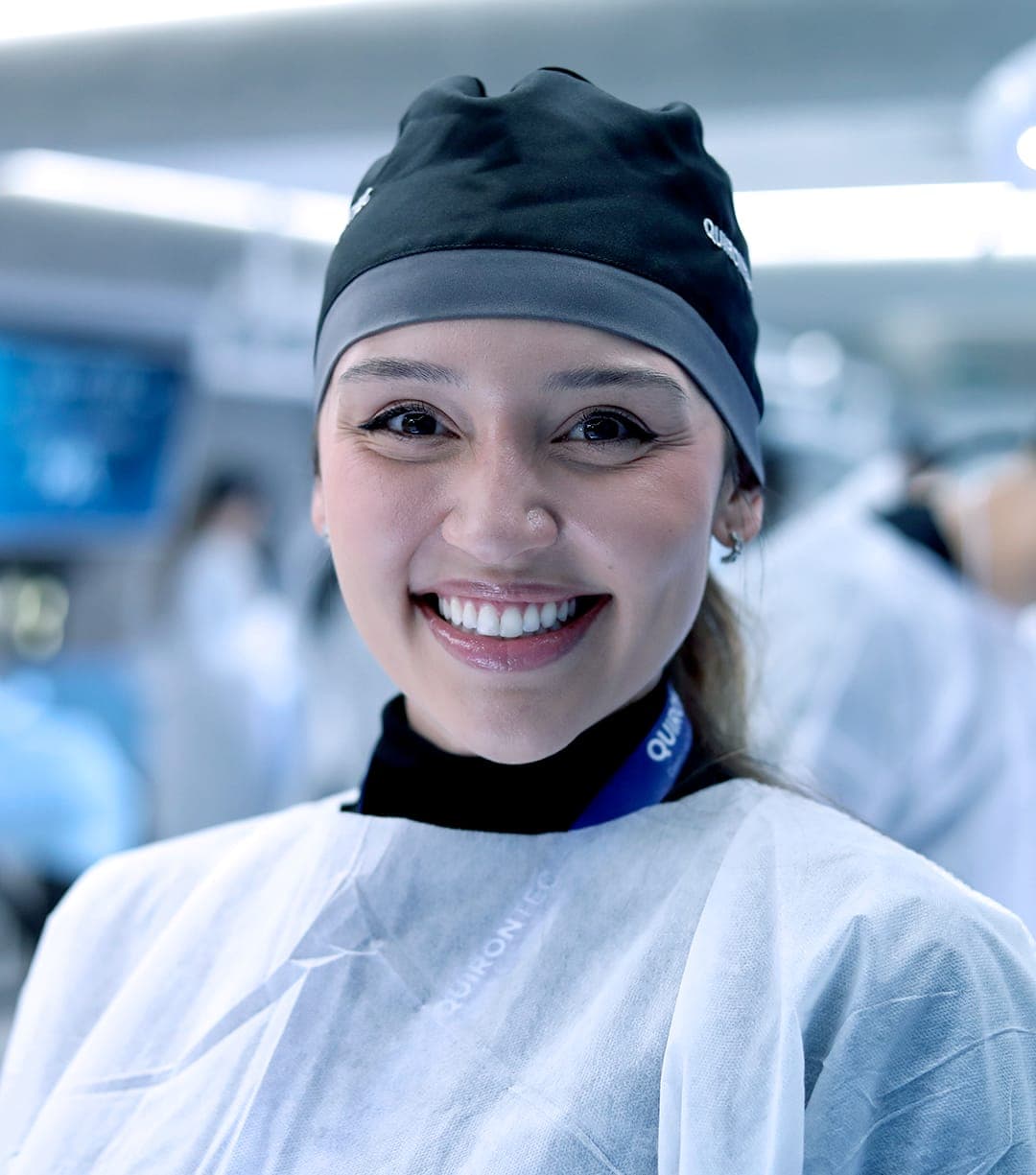 Aluna sorrindo no laboratório, de touca e avental